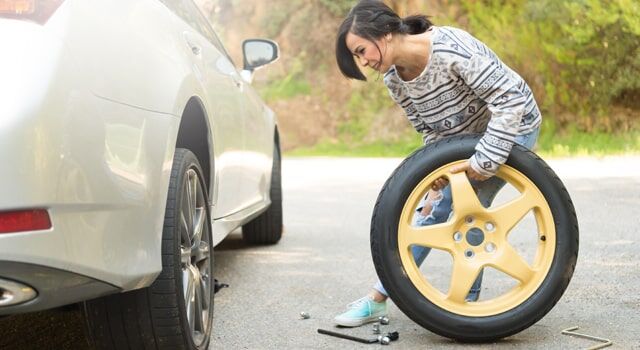 A young car owner changing a flat car tire